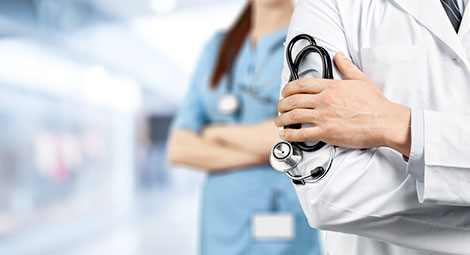 a doctor holding a stethoscope with a nurse in the background